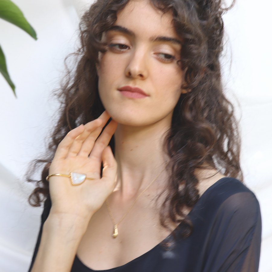 Image is a model wearing a 24K gold plated palm cuff with an asymmetrical moonstone cabochon, handmade by Izaskun  Zabala.