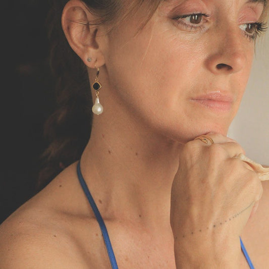 Image is a pair of 24K gold plated earrings with a baroque pearl dangling from a cushion cut stone, handmade by Izaskun Zabala.