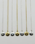 Image is a selection of zodiac necklaces in silver and gold-plate, with a small medallion pendant and star engraved birthstone, handmade by Izaskun Zabala.