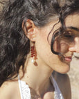 Garnets and pearls drop earrings, handmade by Izaskun Zabala, on model against a blurry background.