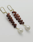 Pair of earrings with briolette garnets and pearl drops on a light gray background, handmade by Izaskun Zabala.
