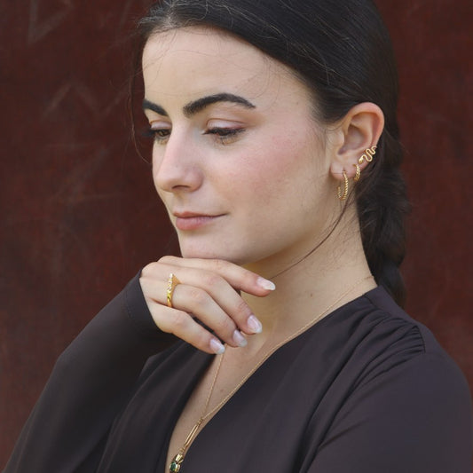 Woman wearing gold-plated hoop earrings and a pyramidal ring, made by artisan Izaskun Zabala.