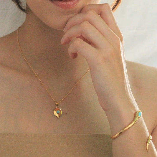 Image is a gold plated disc pendant with a turquoise cabochon center stone and a dainty gold filled chain, handmade by Izaskun Zabala.