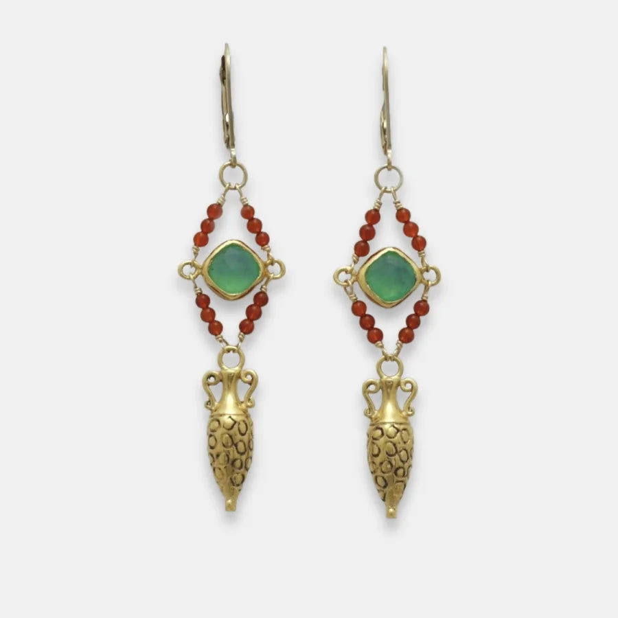 Pair of golden drop amphora earrings with green gemstones and red beads on a white background, handmade by Izaskun Zabala.