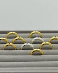 Gold plated and silver rings with an engraved star and gemstones, handmade by Izaskun Zabala, on a gray cushioned display.