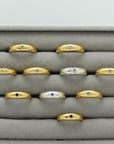 Gold plated and silver rings with an engraved star and gemstones, handmade by Izaskun Zabala, on a gray cushioned display.