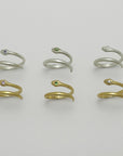 Set of snake-shaped gold plated and silver rings with gemstones on a light gray background, handmade by Izaskun Zabala.