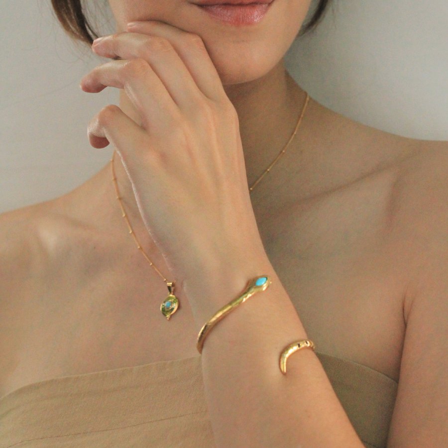Image is a gold plated disc pendant with a turquoise cabochon center stone and a dainty gold filled chain, handmade by Izaskun Zabala.