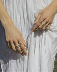 Close-up of hands with multiple snake rings handmade by Izaskun Zabala, on a natural background.