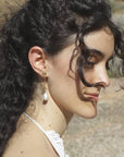 Woman with long dark hair wearing gold snake earrings with a baroque pearl drop, handmade by Izaskun Zabala.