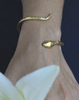 Image is a 24K gold plated snake cuff with garnet eyes, tanzanite and white topaz stones, handmade by Izaskun Zabala.