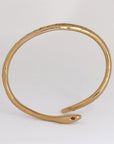 Image is a 24K gold plated snake cuff with garnet eyes, tanzanite and white topaz stones, handmade by Izaskun Zabala.