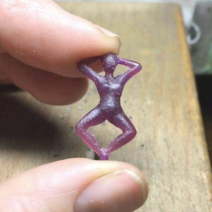 Image is a pair of earrings of a woman's figure dangling from a shell stud, handmade by Izaskun Zabala.