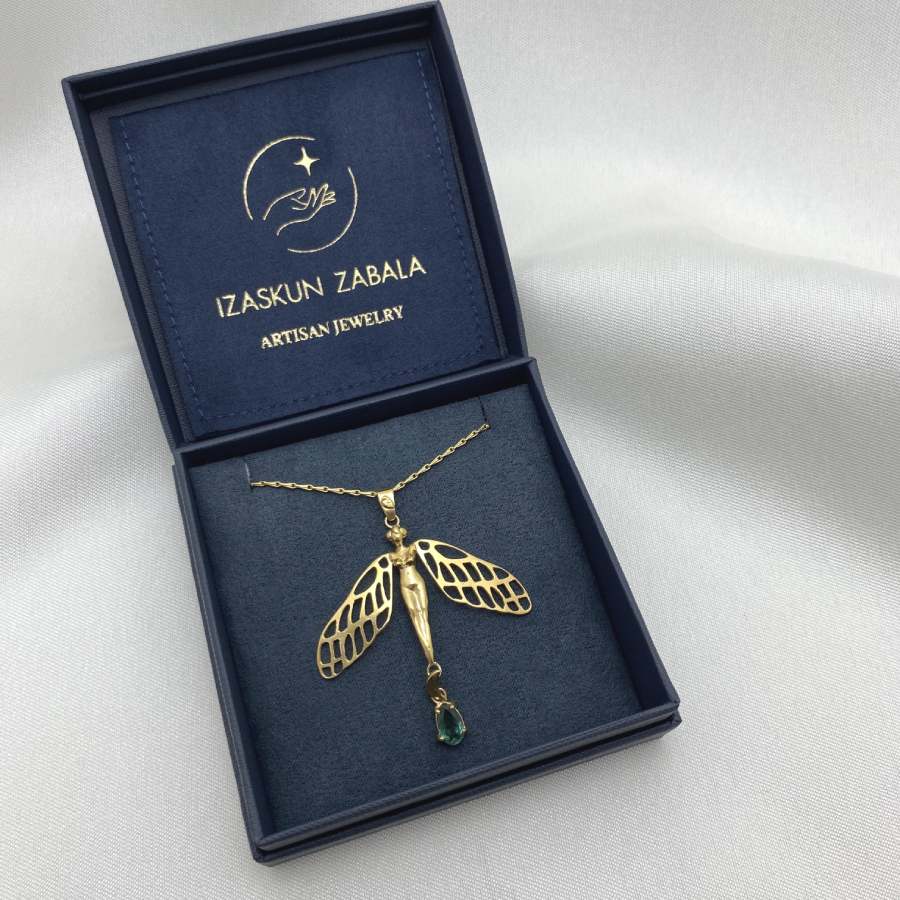 Image is a dragonfly with female body and tourmaline drop gold-plated statement necklace, displayed in the brand's packaging.