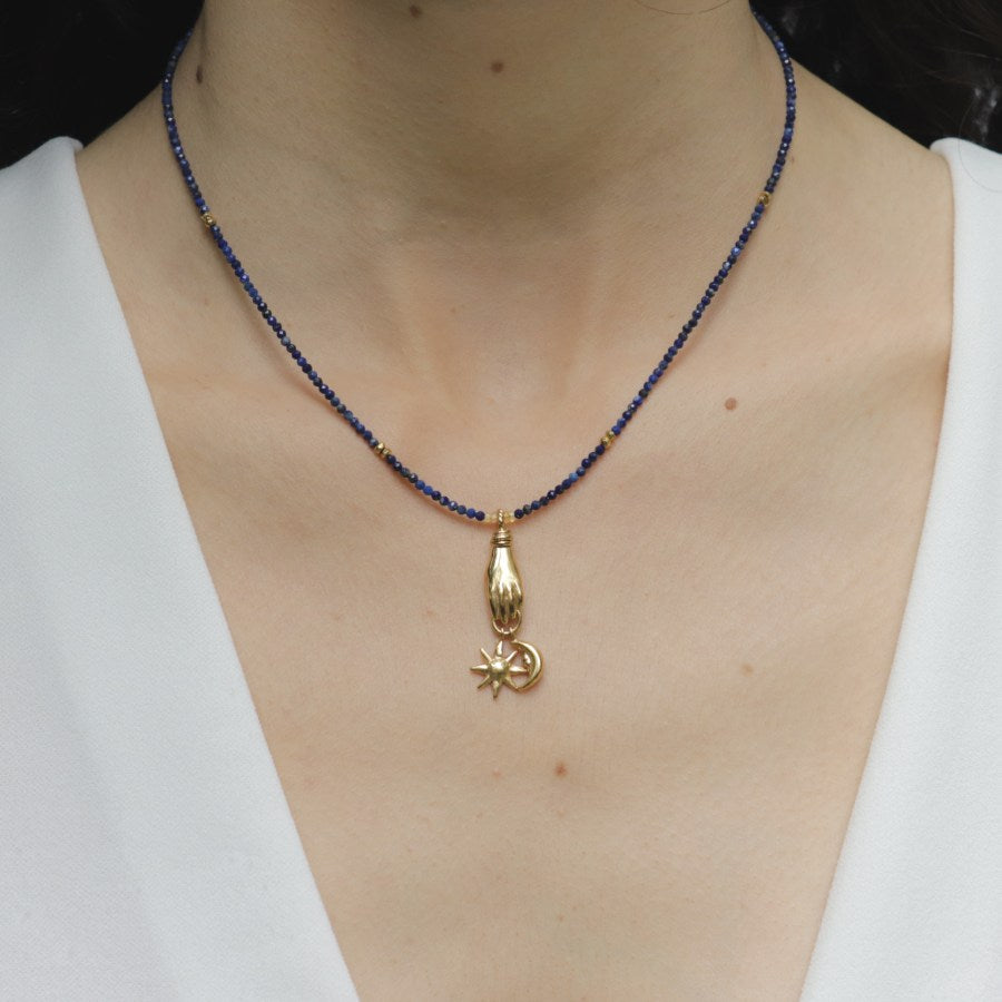 Image is a lapis lazuli beaded chain with gold-plated celestial charms on model, handmade by Izaskun Zabala.