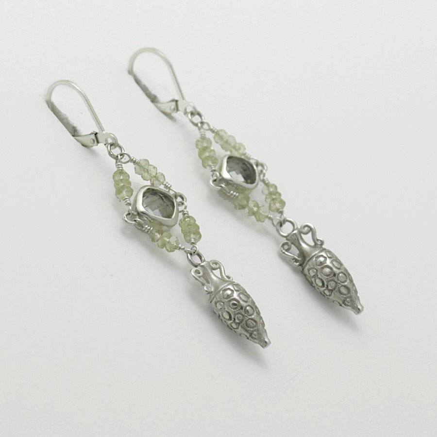 Pair of silver amphora drop earrings with green gemstones on a light gray background, handmade by Izaskun Zabala.