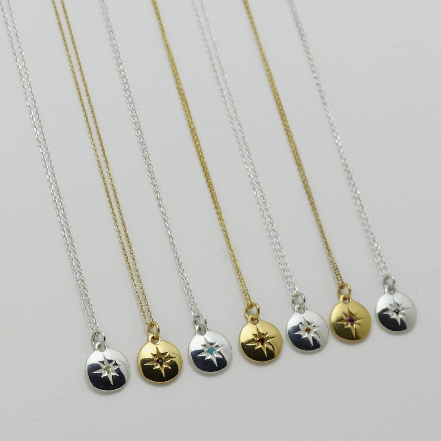 Image is a selection of zodiac necklaces in silver and gold-plate, with a small medallion pendant and star engraved birthstone, handmade by Izaskun Zabala.