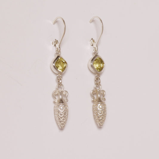Image is a pair of silver earrings with a carved amphora dangling from a cushion cut citrine stone, handmade by Izaskun Zabala.