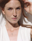 Image is a silver key charm pendant delicate necklace on a model, handmade by Izaskun Zabala.