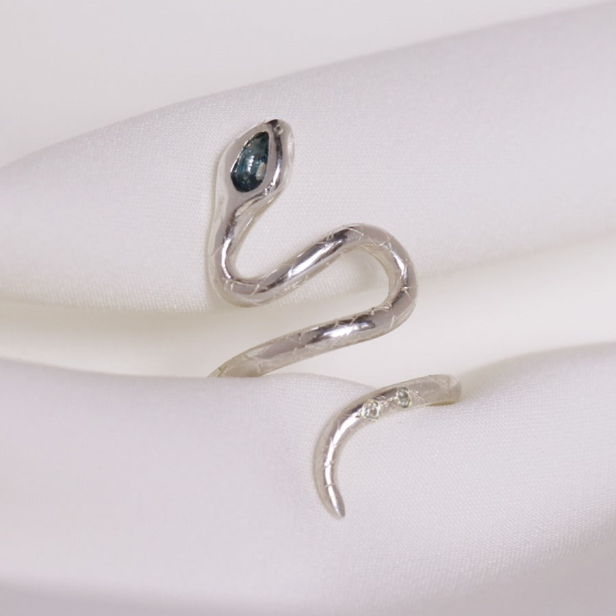 Image is a silver snake ring with a pear shape london topaz and two white topaz in the tail, handmade by Izaskun Zabala.