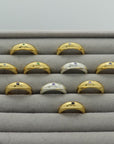 Gold plated and silver rings with an engraved star and gemstones, handmade by Izaskun Zabala, on a gray cushioned display.