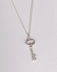 Image is a silver key charm pendant delicate necklace, handmade by Izaskun Zabala.