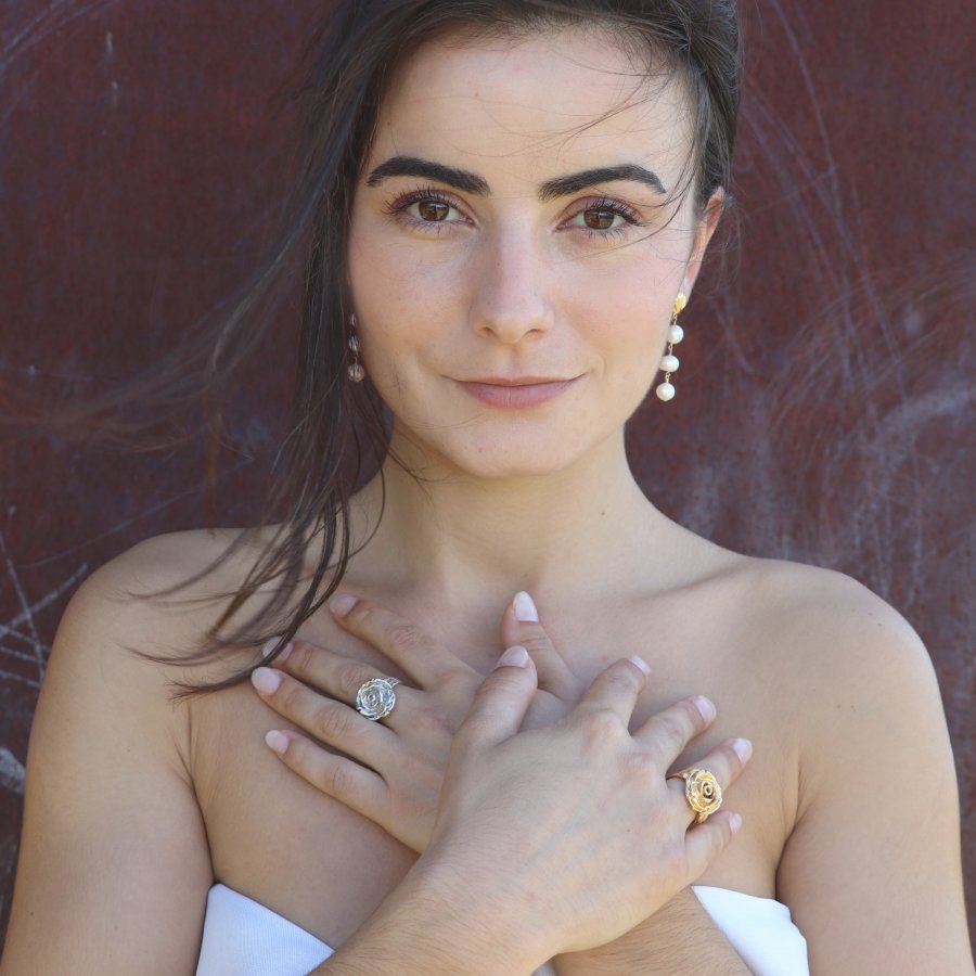 Woman wearing gold-plated rose rings and pearl earrings, handmade by Izaskun Zabala.