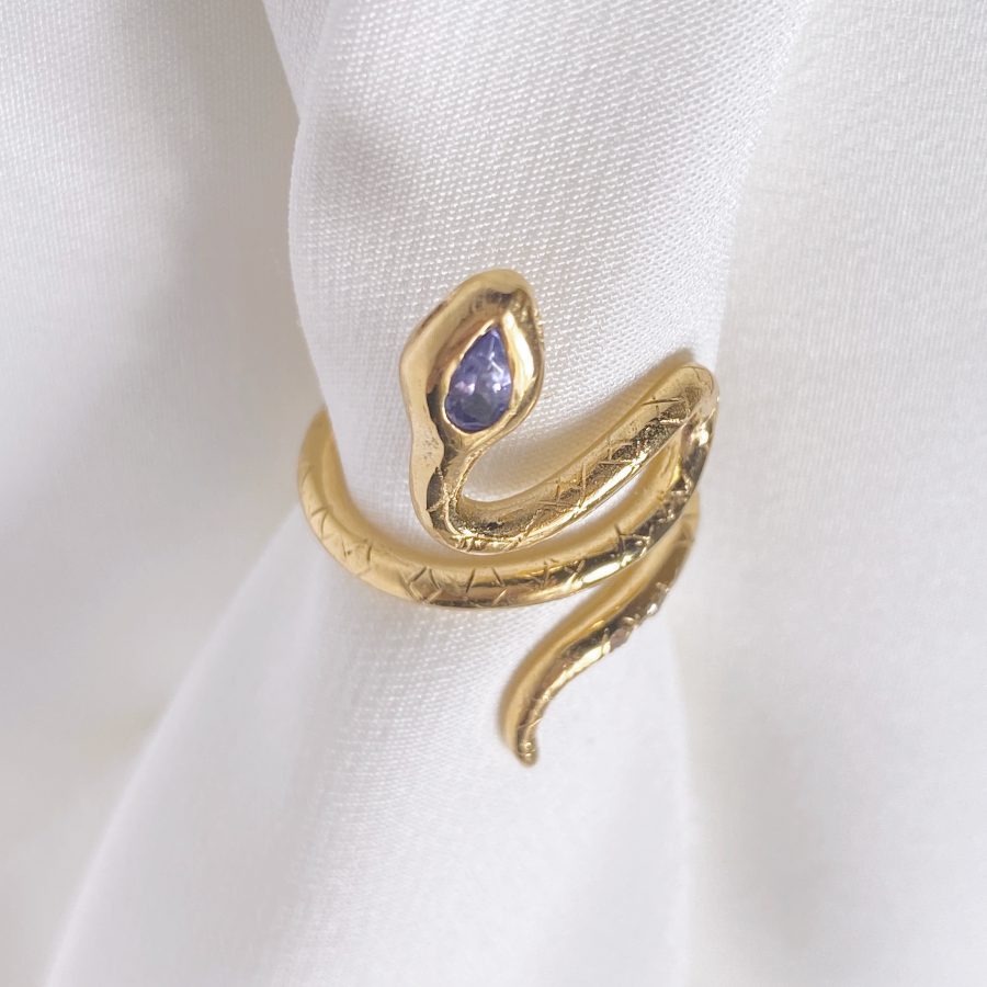 Image is a 24K gold plated snake ring with a pear shape tanzanite and two white sapphires in the tail, handmade by Izaskun Zabala.