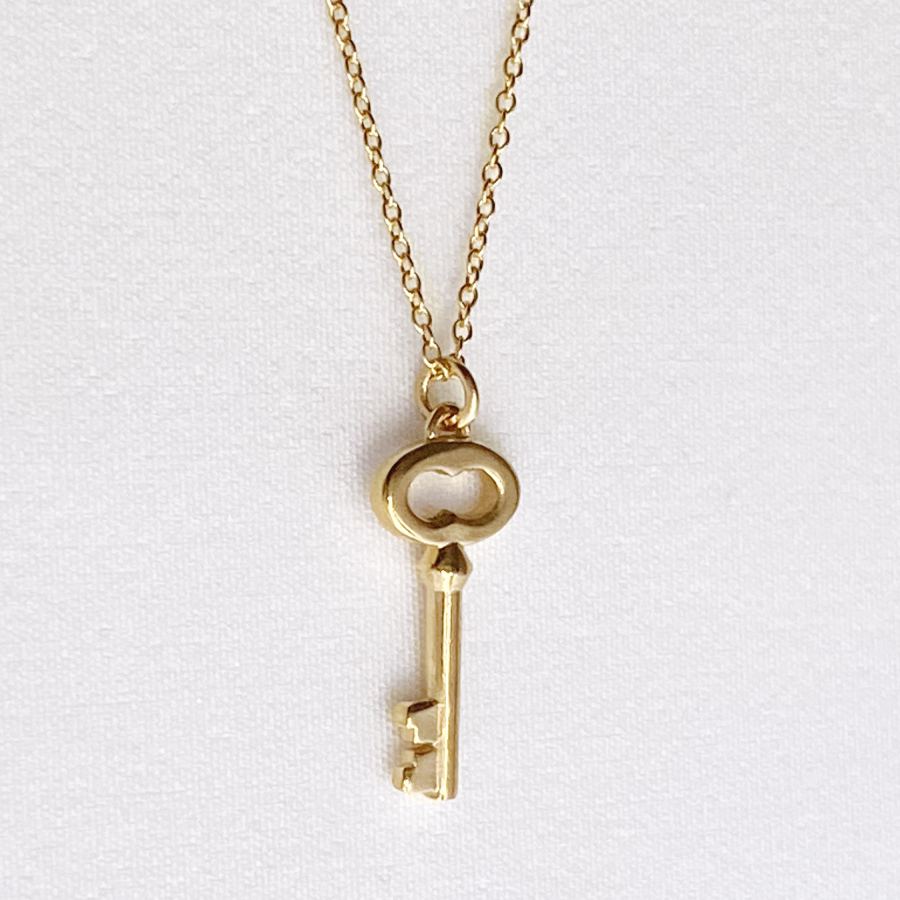 Image is a 24K gold plated key charm pendant delicate necklace, handmade by Izaskun Zabala.