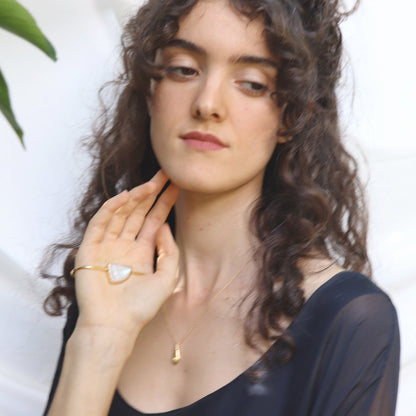 Image is a model wearing a 24K gold plated palm cuff with an asymmetrical moonstone cabochon, handmade by Izaskun  Zabala.