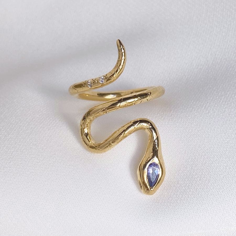 Image is a 24K gold plated snake ring with a pear shape tanzanite and two white sapphires in the tail, handmade by Izaskun Zabala.