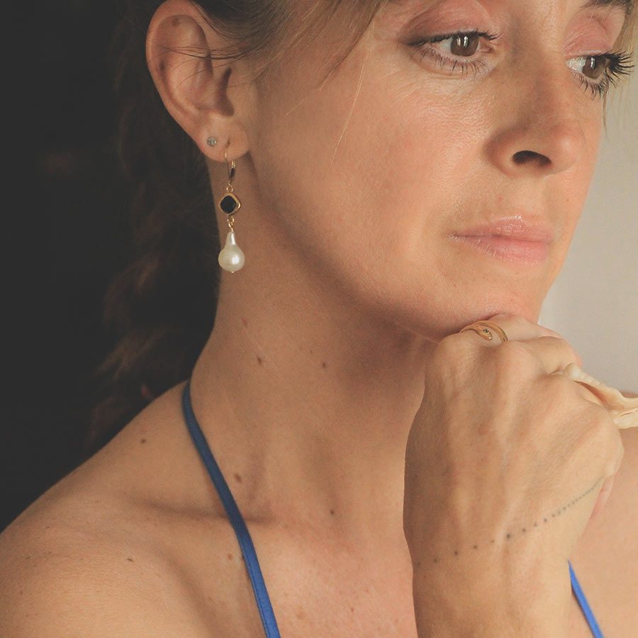 Image is a pair of 24K gold plated earrings with a baroque pearl dangling from a cushion cut stone, handmade by Izaskun Zabala.