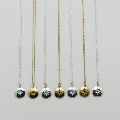 Image is a selection of zodiac necklaces in silver and gold-plate, with a small medallion pendant and star engraved birthstone, handmade by Izaskun Zabala.