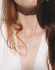 Image is a model wearing a silver disc pendant necklace representing the sun, handmade by Izaskun Zabala. 