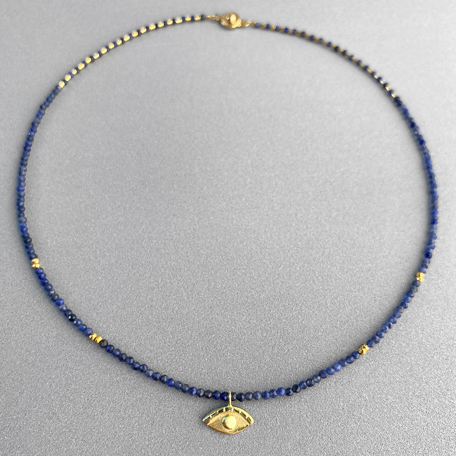 Image is an iolite bead choker with an 18K gold plated small eye pendant, handmade by Izaskun Zabala.