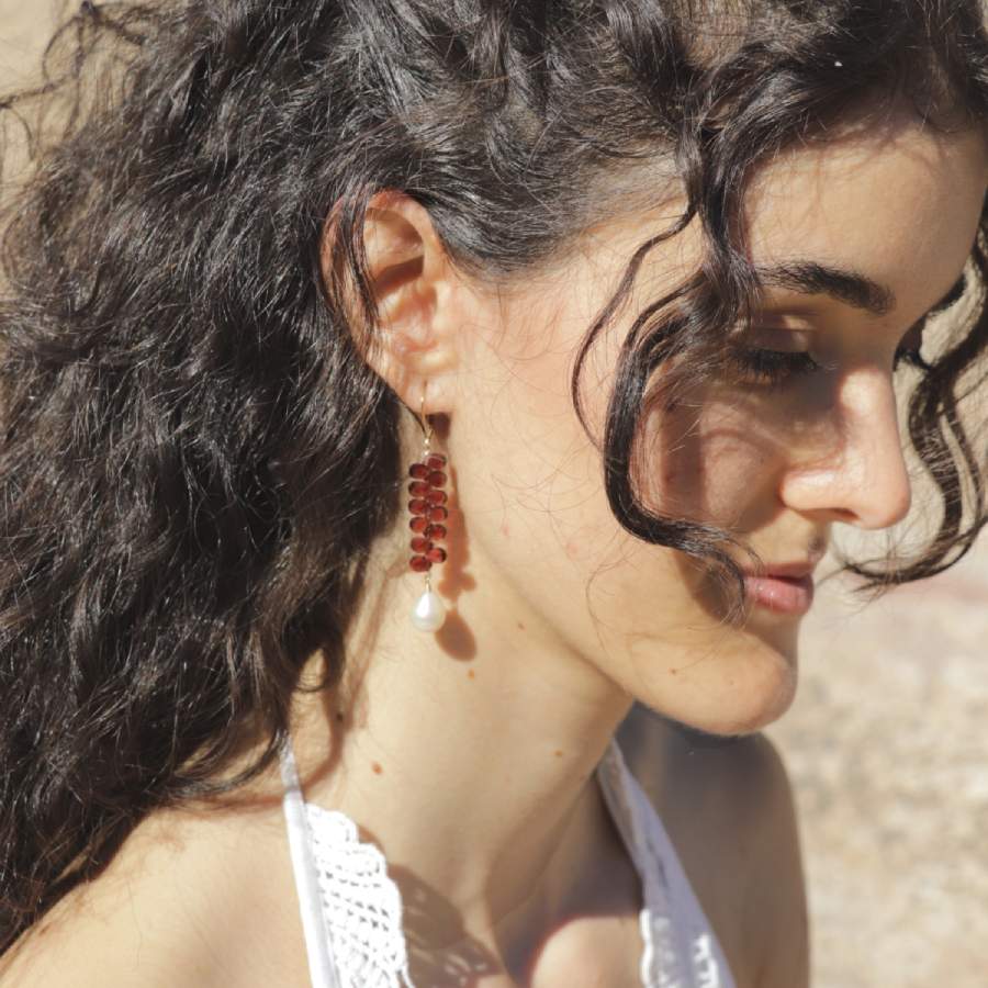 Garnets and pearls drop earrings, handmade by Izaskun Zabala, on model against a blurry background.