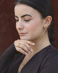 Woman wearing gold-plated hoop earrings and a pyramidal ring, made by artisan Izaskun Zabala.