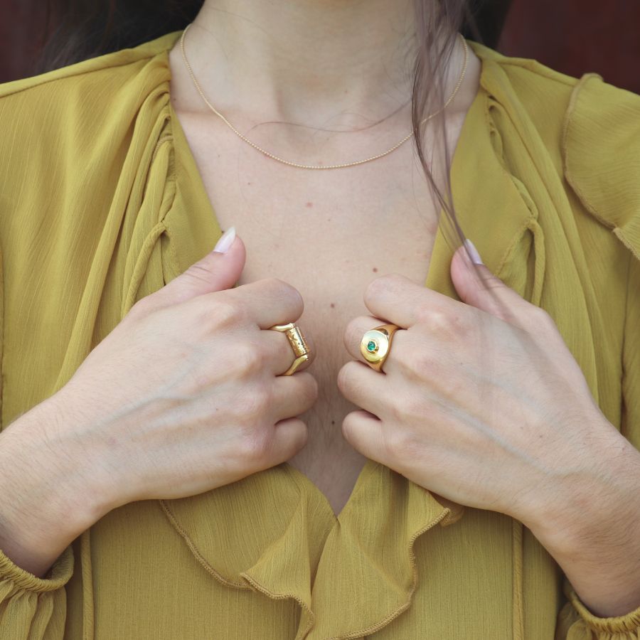 Woman wearing gold-plated artisan rings with a yellow shirt.