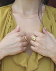 Woman wearing gold-plated artisan rings with a yellow shirt.