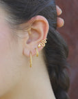 Close-up of a woman wearing gold-plated hoop earrings and snake stud, handmade by Izaskun Zabala.