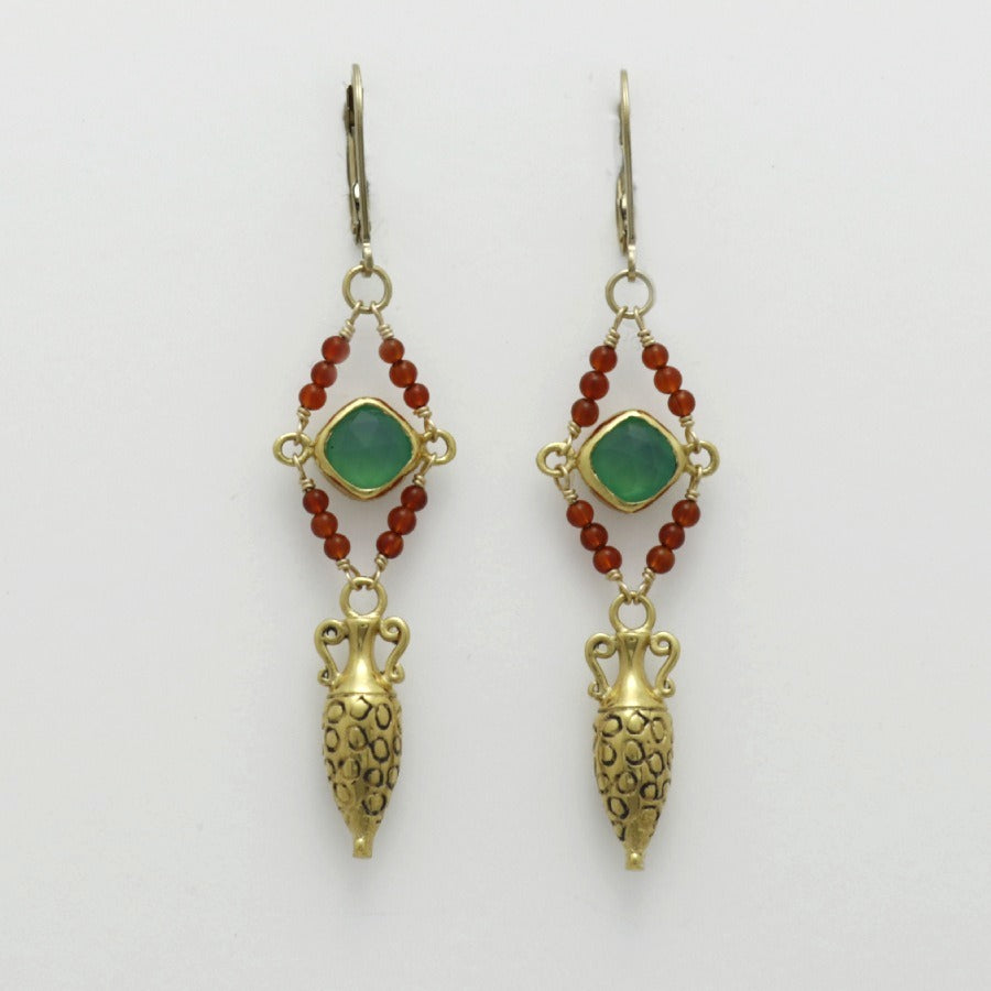 Pair of golden drop amphora earrings with green gemstones and red beads on a white background, handmade by Izaskun Zabala.