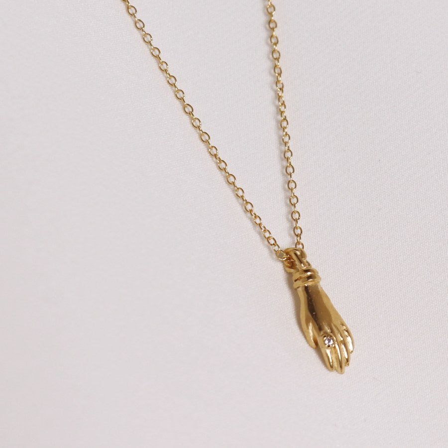 Image is a gold plated hand pendant necklace with white sapphire ring, handmade by Izaskun Zabala.