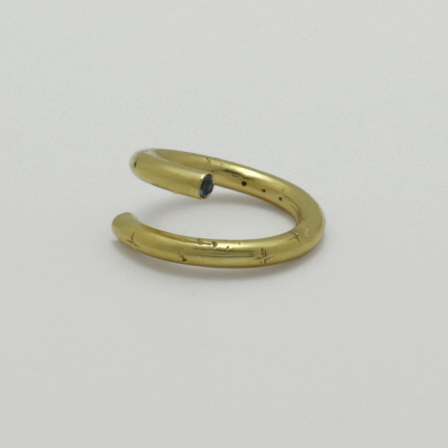 Golden ring with a blue topaz stone on a light gray background, handmade by Izaskun Zabala.