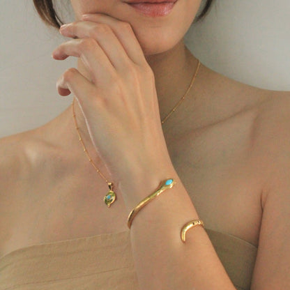 Image is a gold plated disc pendant with a turquoise cabochon center stone and a dainty gold filled chain, handmade by Izaskun Zabala.