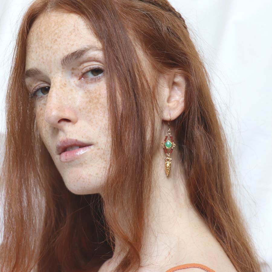 Image is a model wearing 24K gold plated drop earrings with a carved amphora, a cushion cut chrysoprase stone and carnelian beads, handmade by Izaskun Zabala.