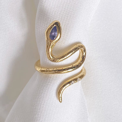 Image is a 24K gold plated snake ring with a pear shape tanzanite and two white topaz in the tail, handmade by Izaskun Zabala.