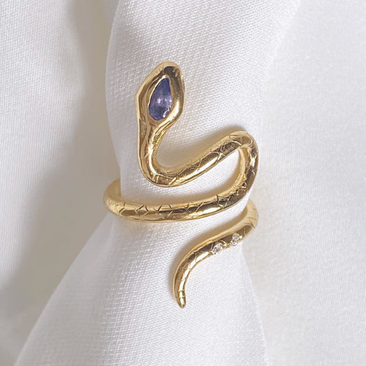 Image is a 24K gold plated snake ring with a pear shape tanzanite and two white topaz in the tail, handmade by Izaskun Zabala.