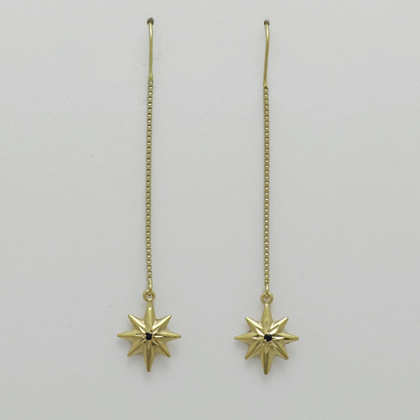 Gold-plated star-shaped dangling earrings with black gemstones, artisan made by Izaskun Zabala.