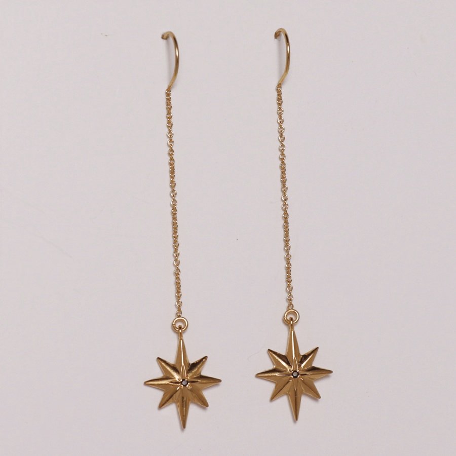 Image is a pair of 24K gold plated dangling star with a tiny black spinel earrings, handmade by Izaskun Zabala.