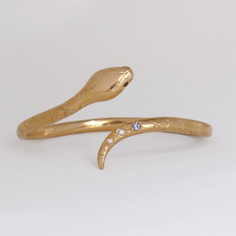 Image is a 24K gold plated snake cuff with garnet eyes, tanzanite and white topaz stones, handmade by Izaskun Zabala.